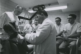 Dental faculty works on patient as students look on