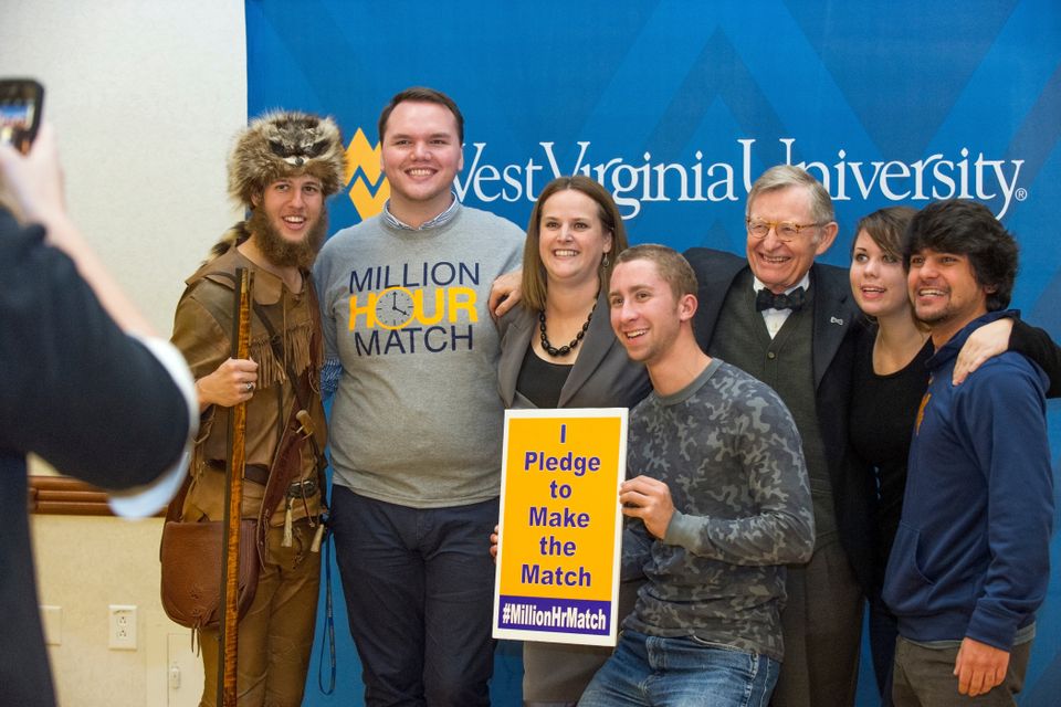 President Gordon Gee posing for a photo with students who are holding a sign that says "I pledge to make the match" 