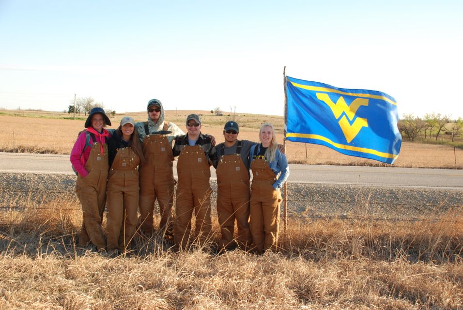 WVU's Soil Judging Team in a field with a "Flying WV" flag 