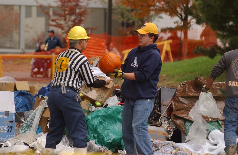 Workers survey a pumpkin for breaks after it was dropped from the top of the Engineering Sciences Building