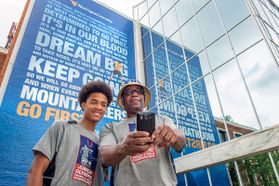 Father and son take a selfie in front of the Mountainlair banner